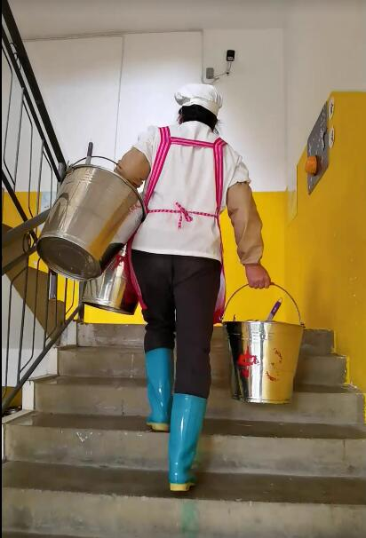 9、提着三个桶正在派送餐具的食堂阿姨.png
